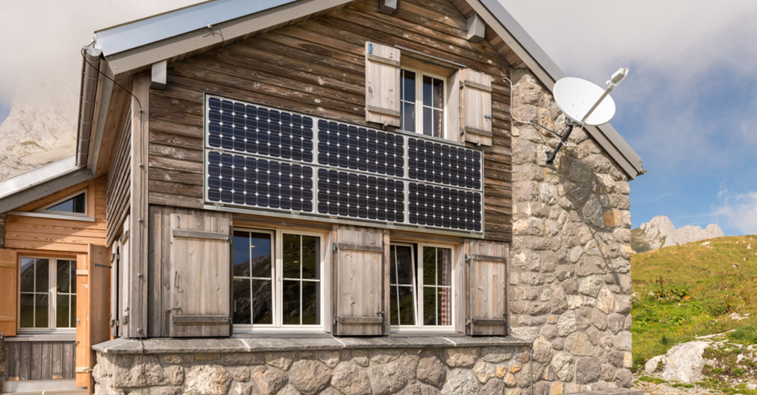 Alpines Einfamilienhaus aus Stein und Holz mit Photovoltaik-Paneelen an der Fassade